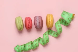 Taśma miarowa z makaronami na różowym tle