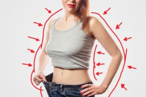 Młoda kobieta w duży dżinsach i szarym topie prezentująca skuteczne odchudzanie