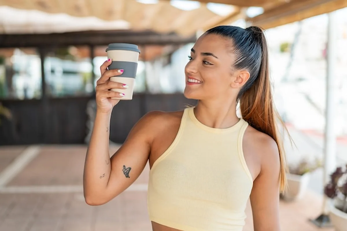 Młoda kobieta trzyma kawę na wynos na świeżym powietrzu