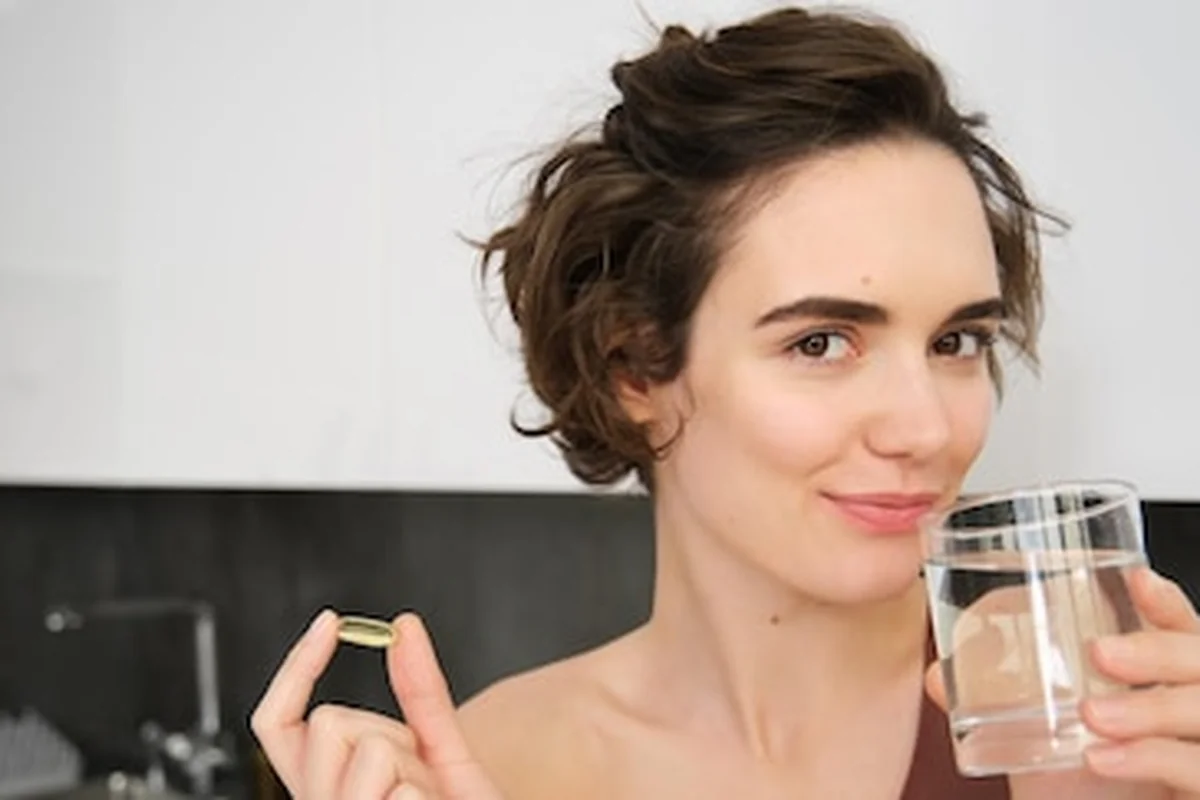 Młoda kobieta biorąca suplementy z wodą