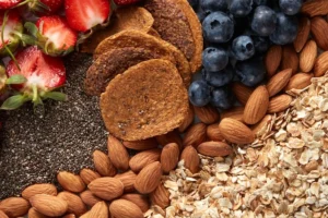 Zestaw składników na talerzu: płatki owsiane, muesli, migdały, jagody i truskawki