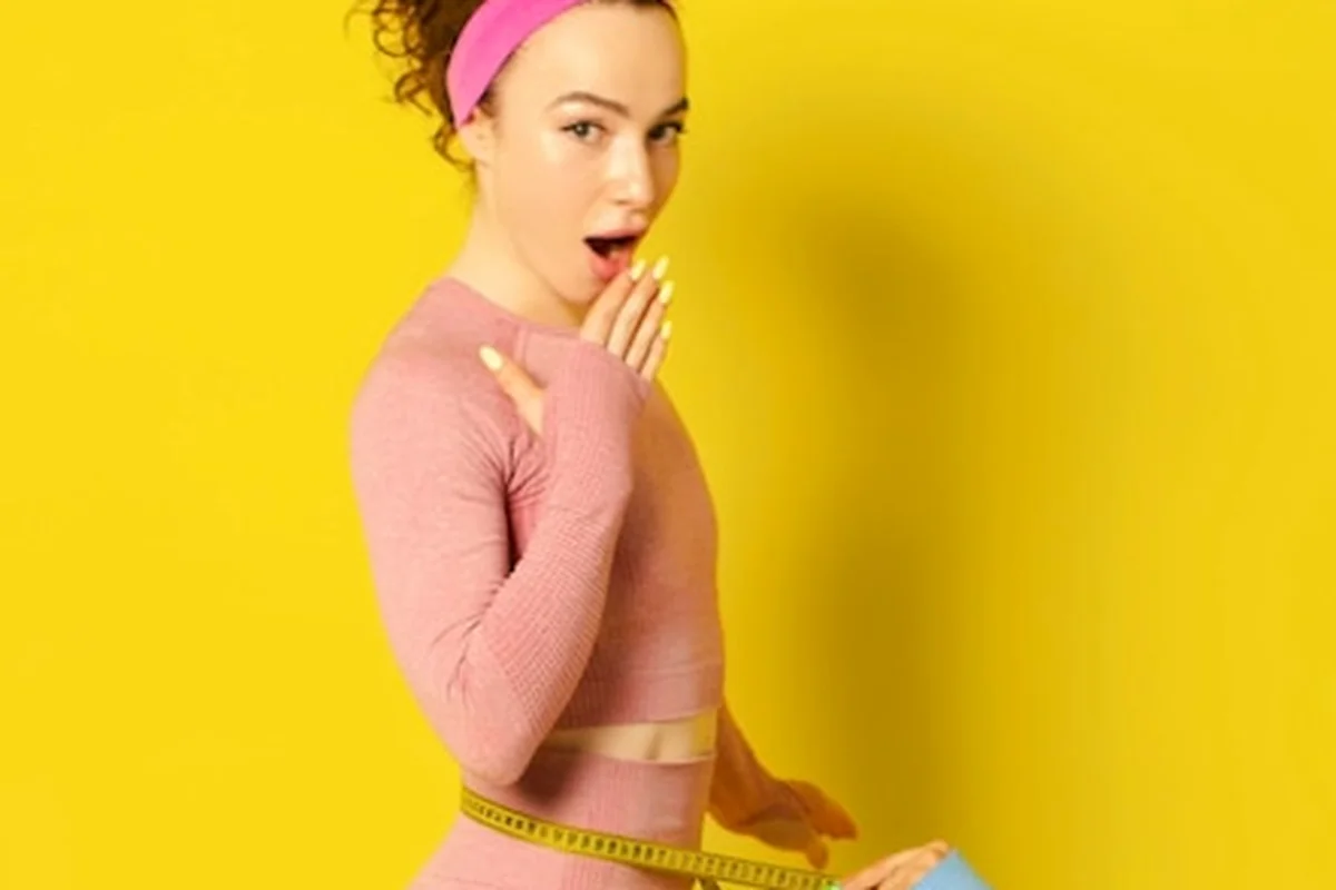 Kobieta mierzy taśmą brzuch w stroju sportowym